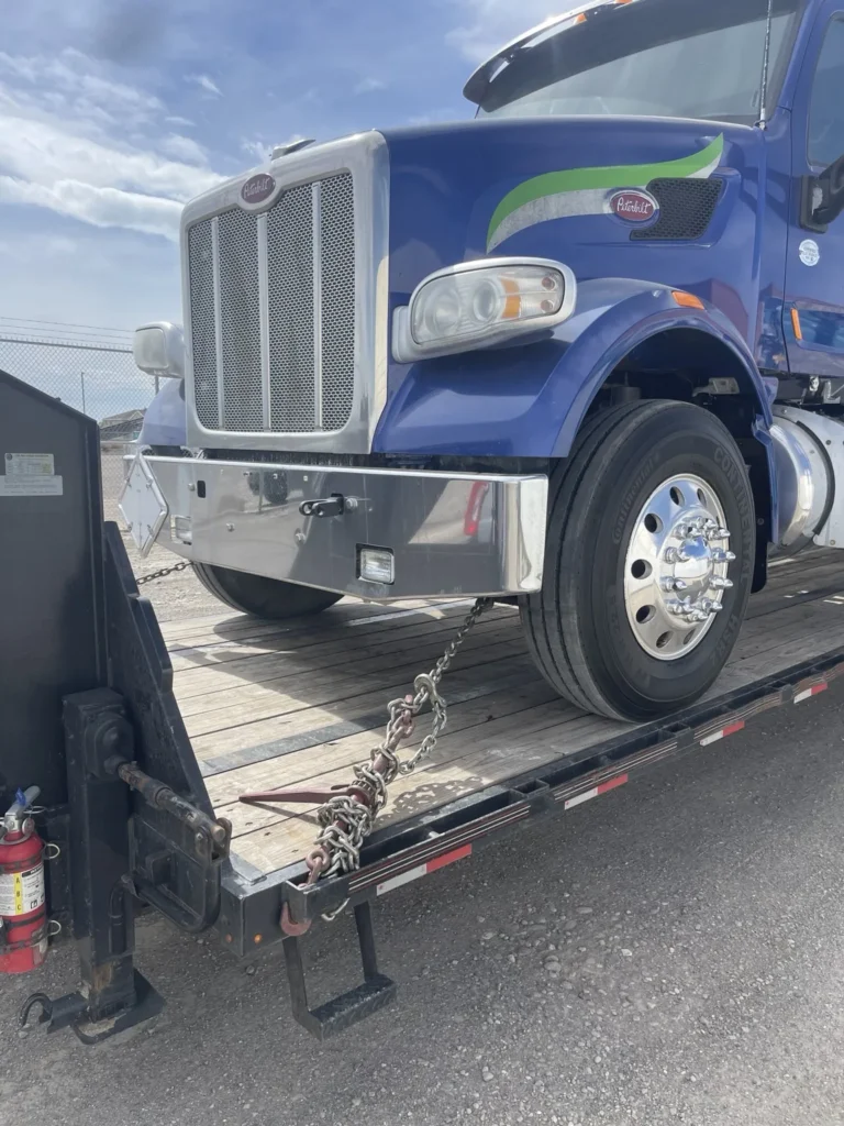 Blue conventional tractor positioned on a flatbed trailer