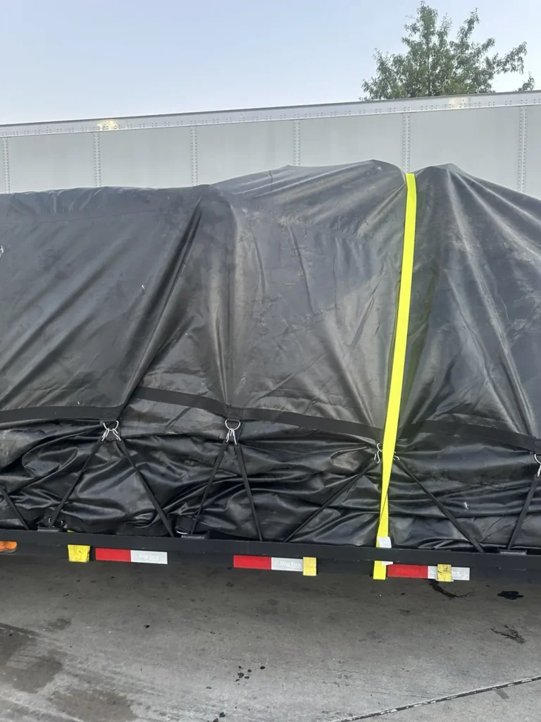 Rear view of a black-tarped load with a vertical yellow strap