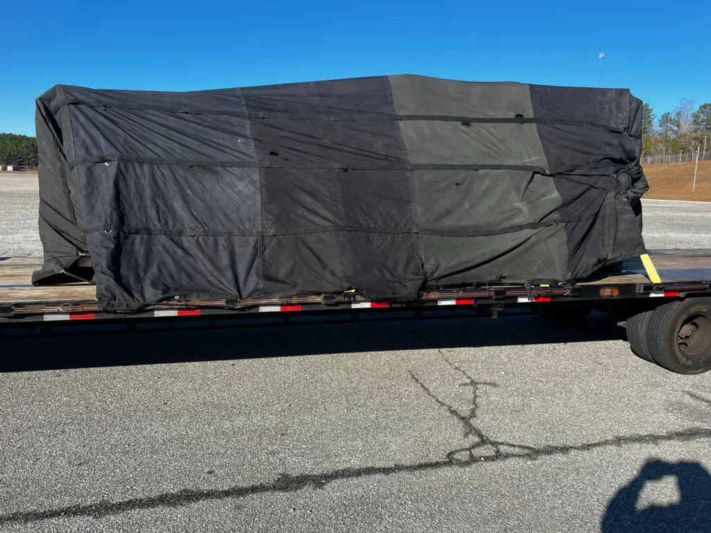 Long side view of a rectangular load fully covered by a black tarp