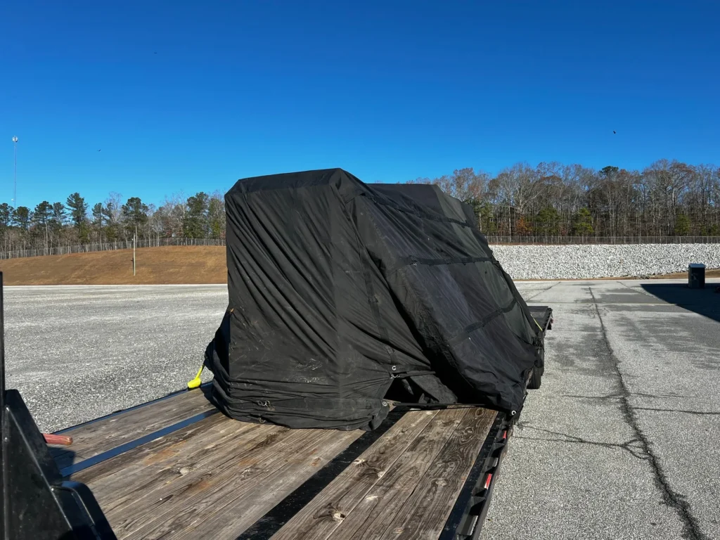 Compact irregular load protected by a black tarp on a flatbed deck