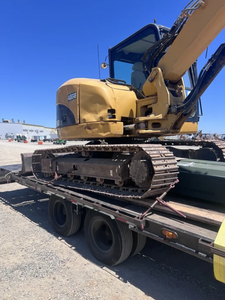 Tracked excavator positioned on a flatbed trailer under clear daylight