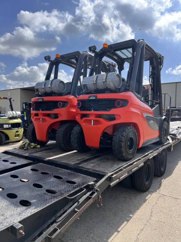 Compact red skid-steer loader positioned on a flatbed trailer