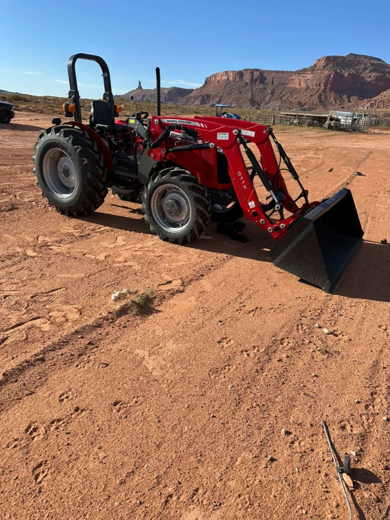 Red agricultural tractor with front loader photographed in a desert work setting