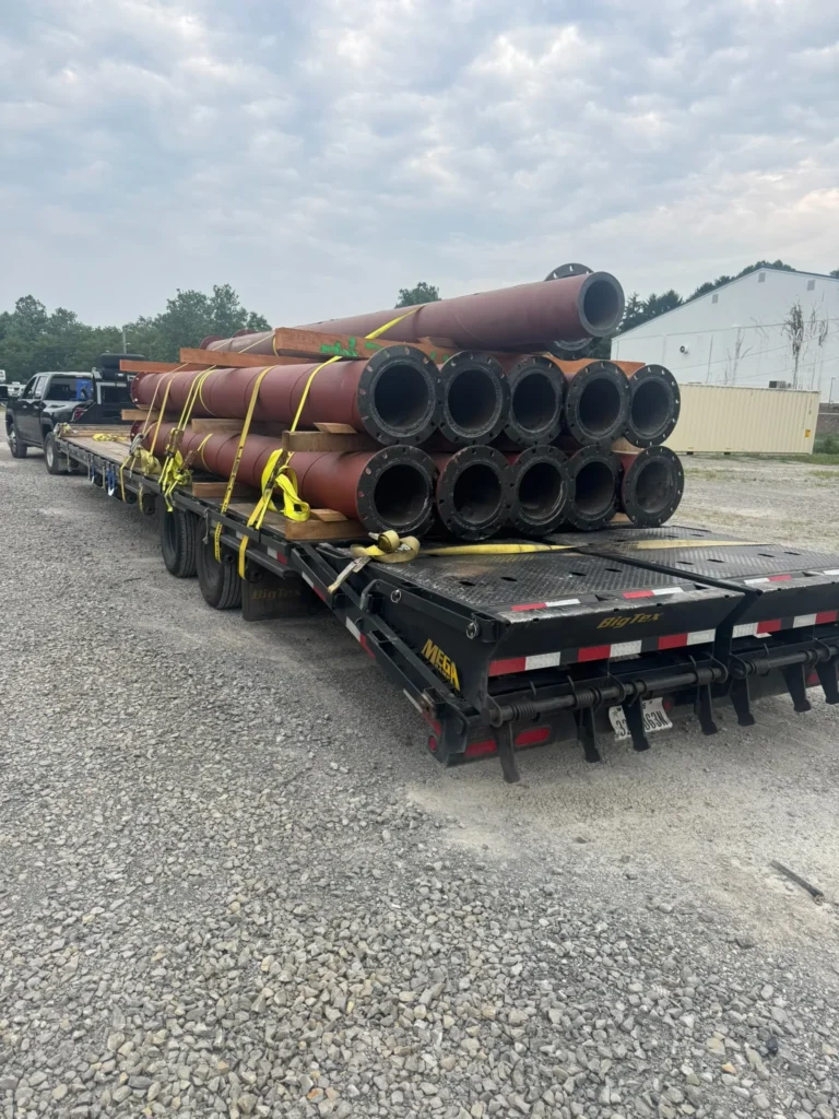 Bundled cylindrical pipe or tubular material secured lengthwise on a flatbed