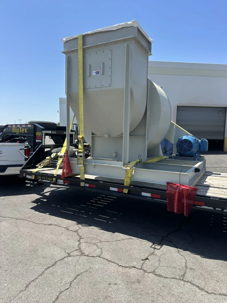 Industrial blower assembly positioned and strapped on a flatbed trailer