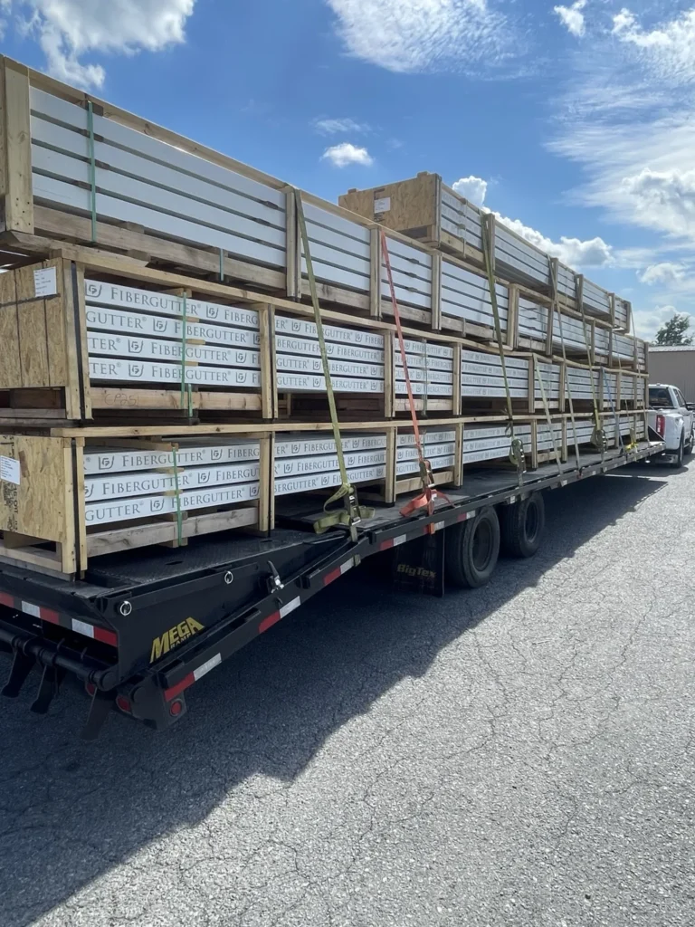 Long packaged materials secured along a flatbed with multiple straps